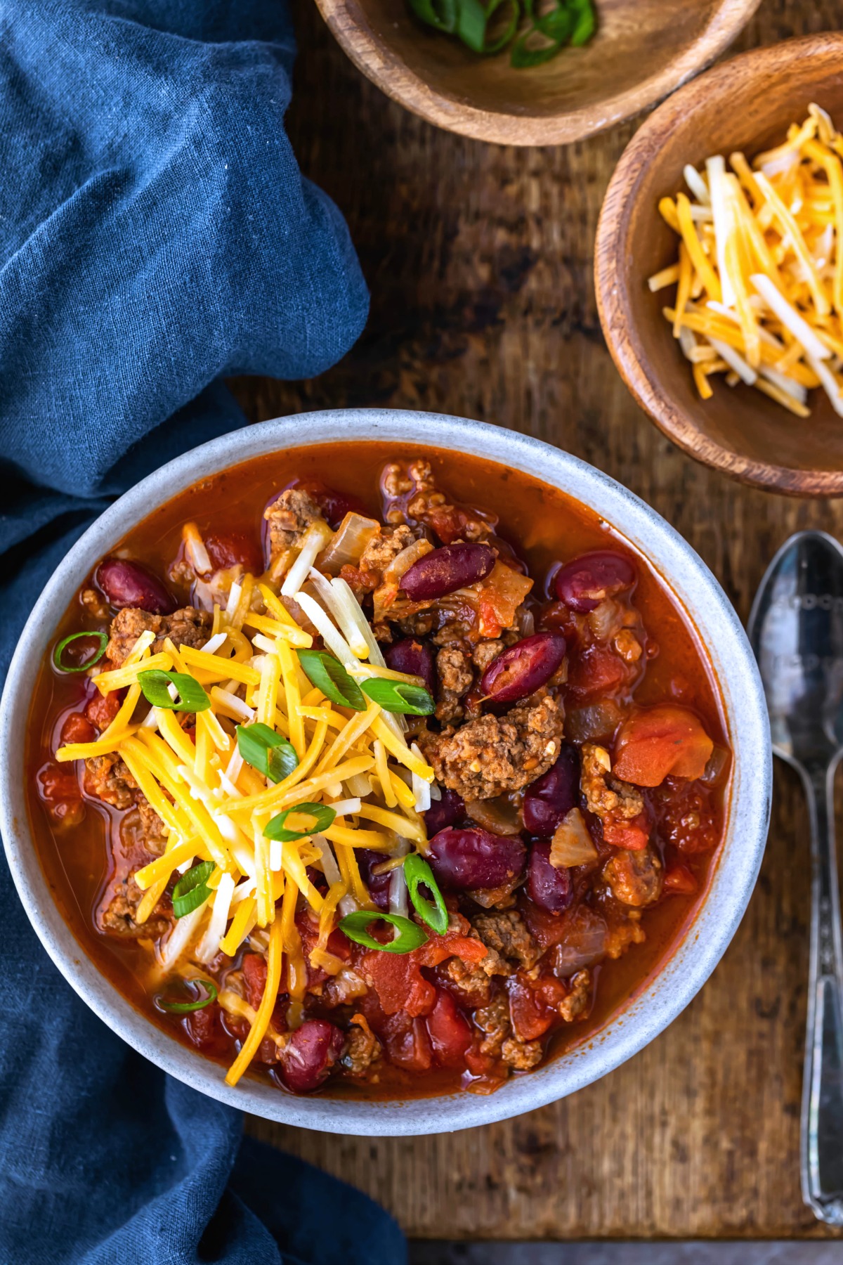 Bowl of instant pot chili topped with sliced green onions and shredded cheese