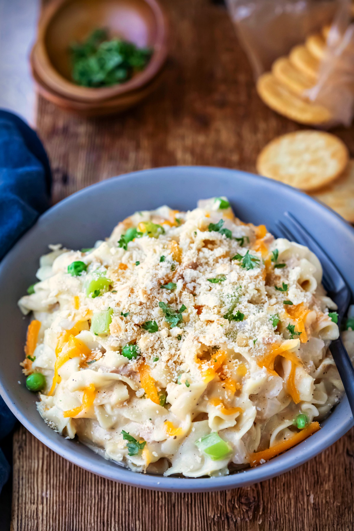 Blue dish of instant pot tuna noodle casserole on a wooden cutting board