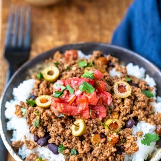 Plate of beef picadillo over black beans and rice