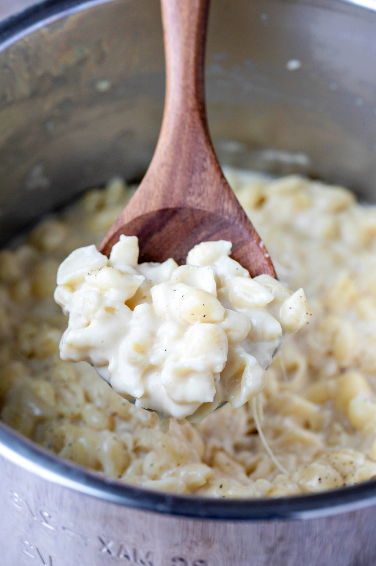 wooden spoon holding a scoop of white cheddar mac and cheese