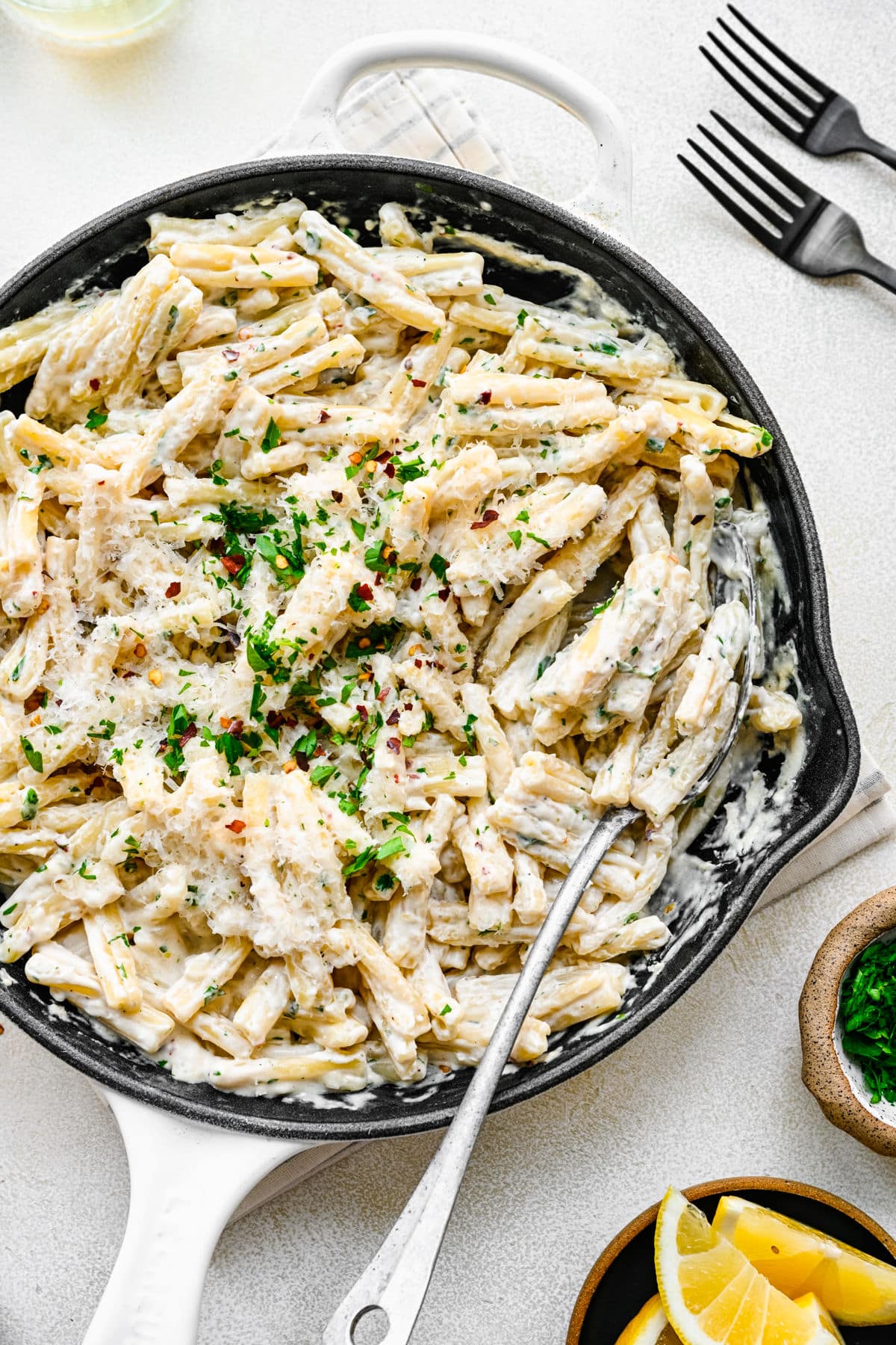 A spoon in a skillet full of cream cheese pasta. 