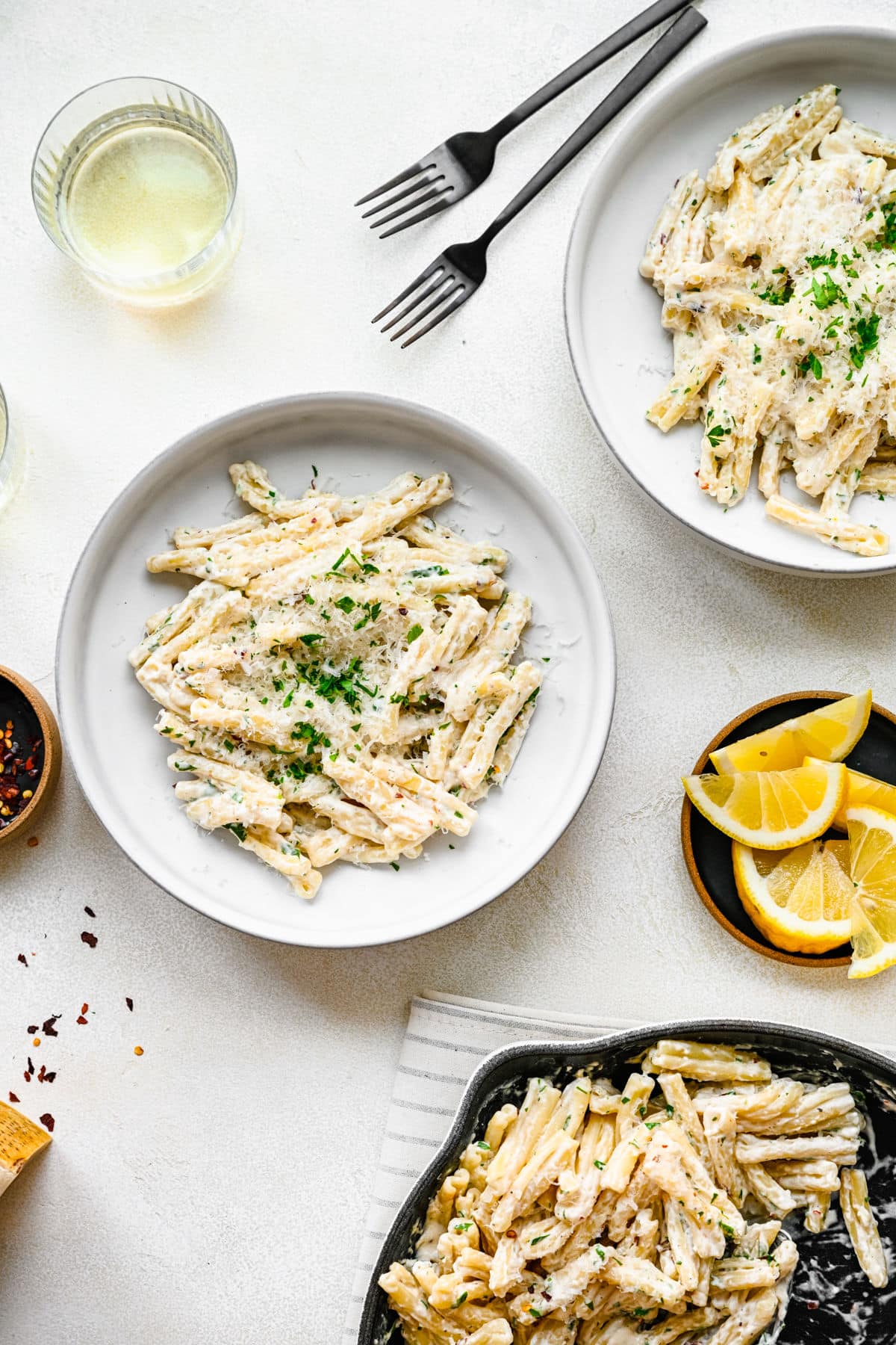 Two plates of cream cheese pasta next to the skillet. 