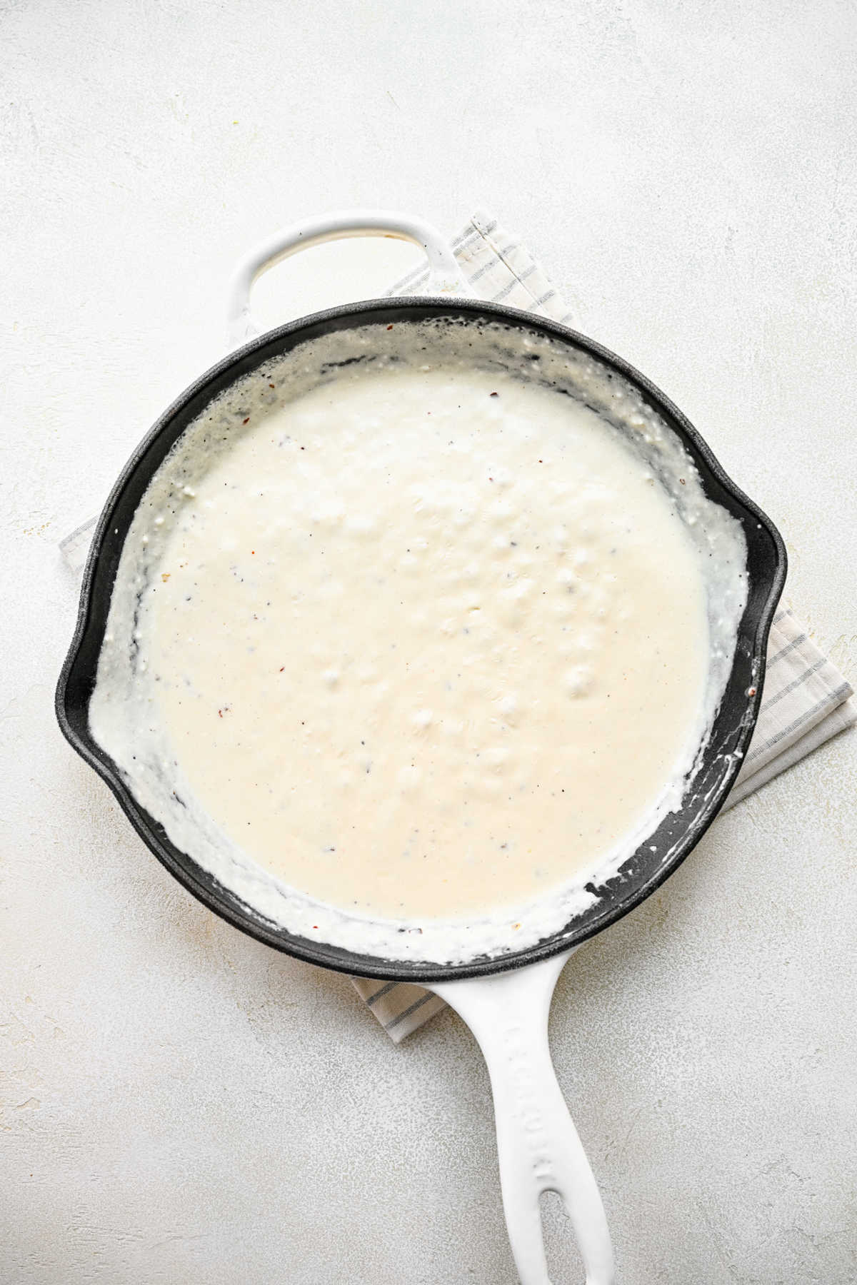 Reserved pasta water in cream cheese mixture in a skillet.