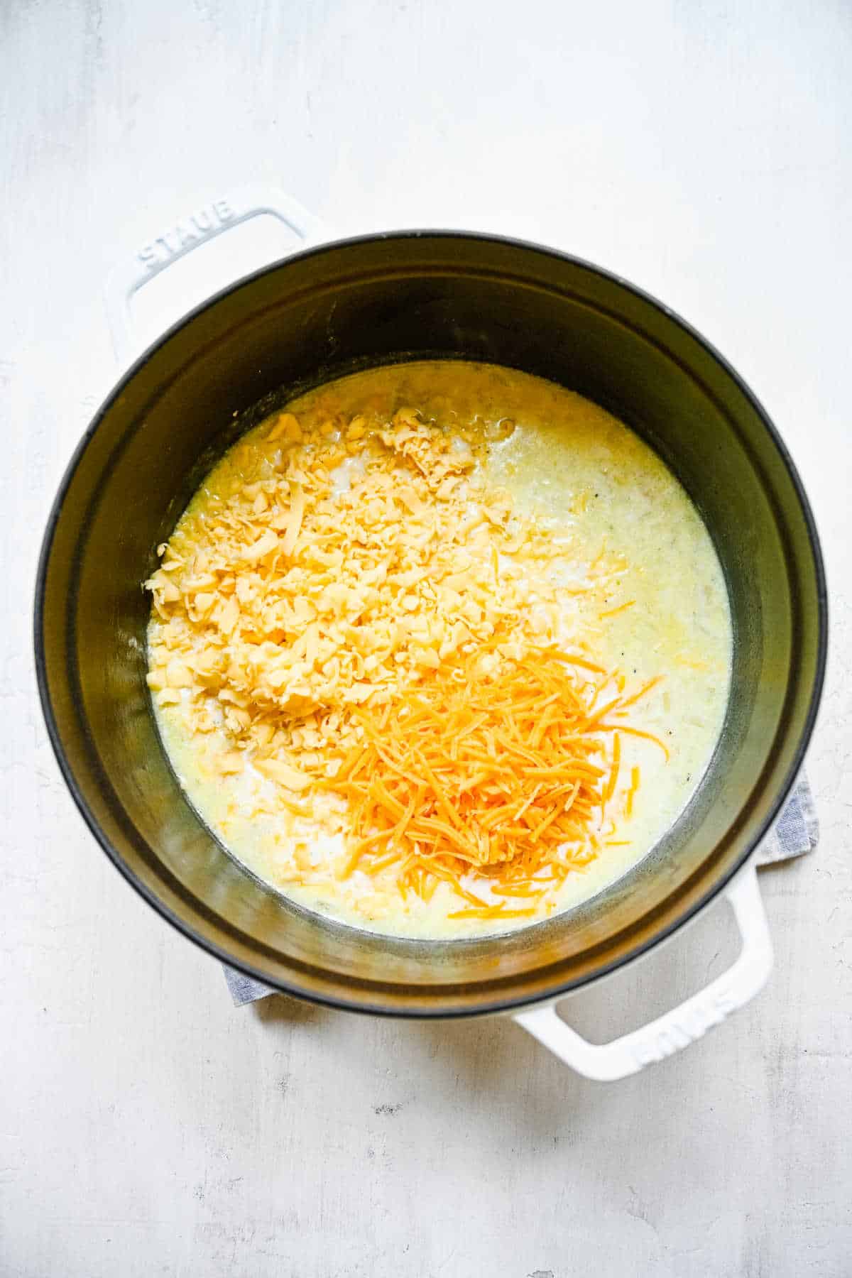 Shredded gouda and cheddar cheeses in milk mixture. 