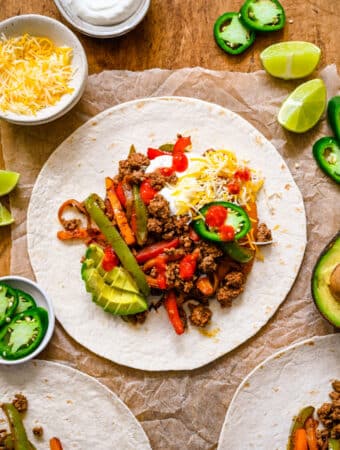 Ground beef fajitas topped with cheese avocado and jalapeno on a flour tortilla.