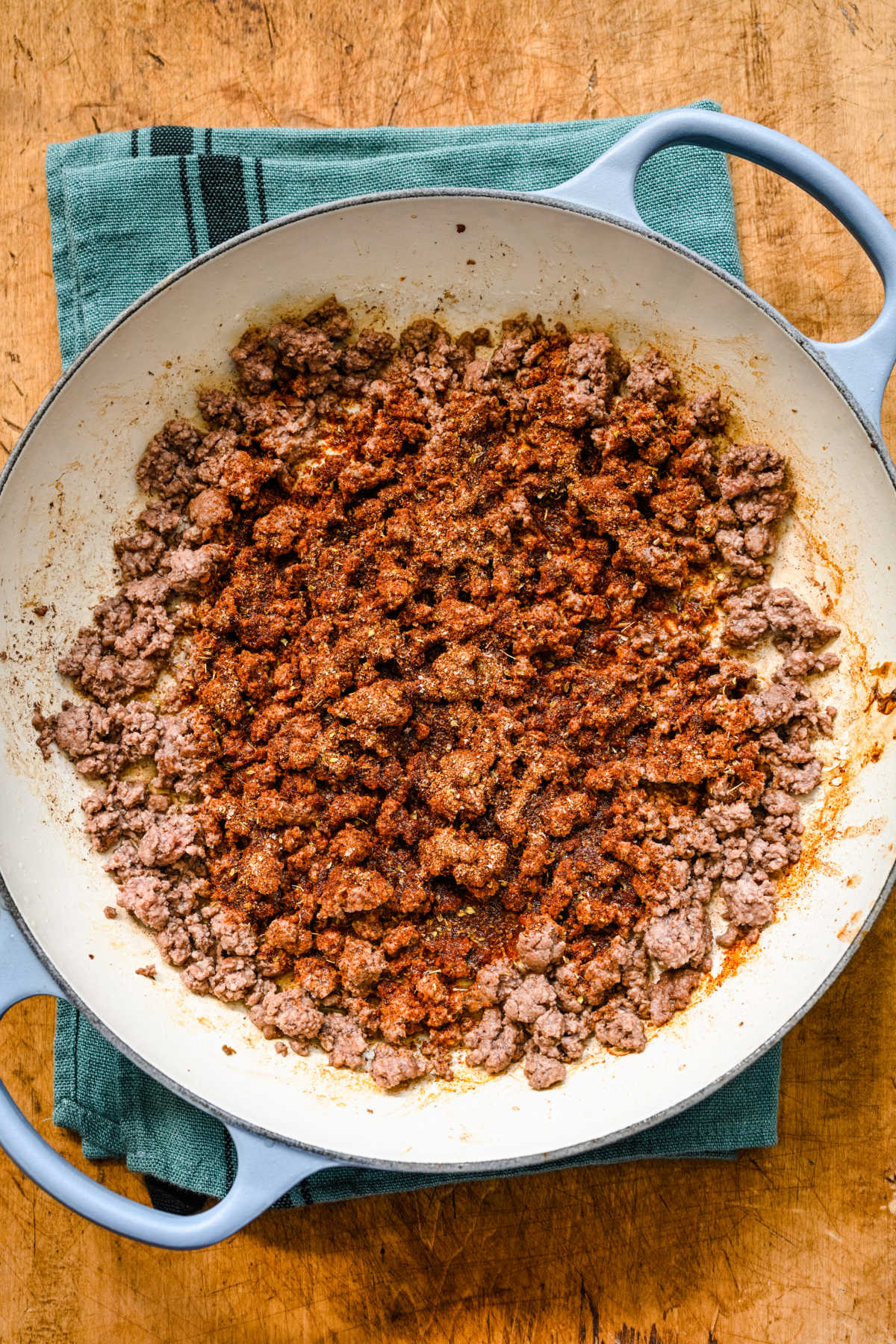 Spices on top of ground beef in a Dutch oven.