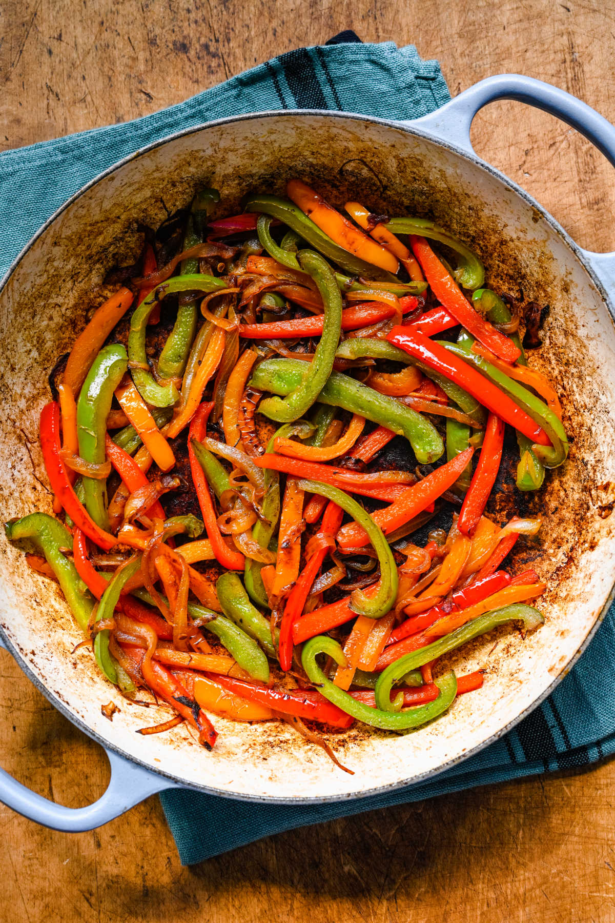 Cooked strips of onion and bell pepper in a Dutch oven.