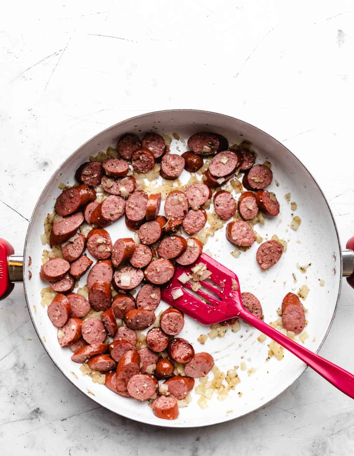 Sliced kielbasa and onion in a large skillet.