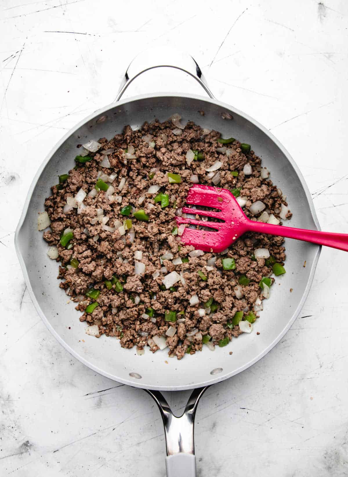 Garlic stirred into ground beef and vegetable mixture in a skillet.