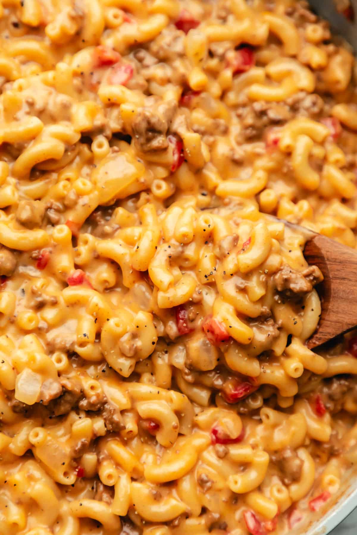 A wooden spoon scooping up cheeseburger macaroni.