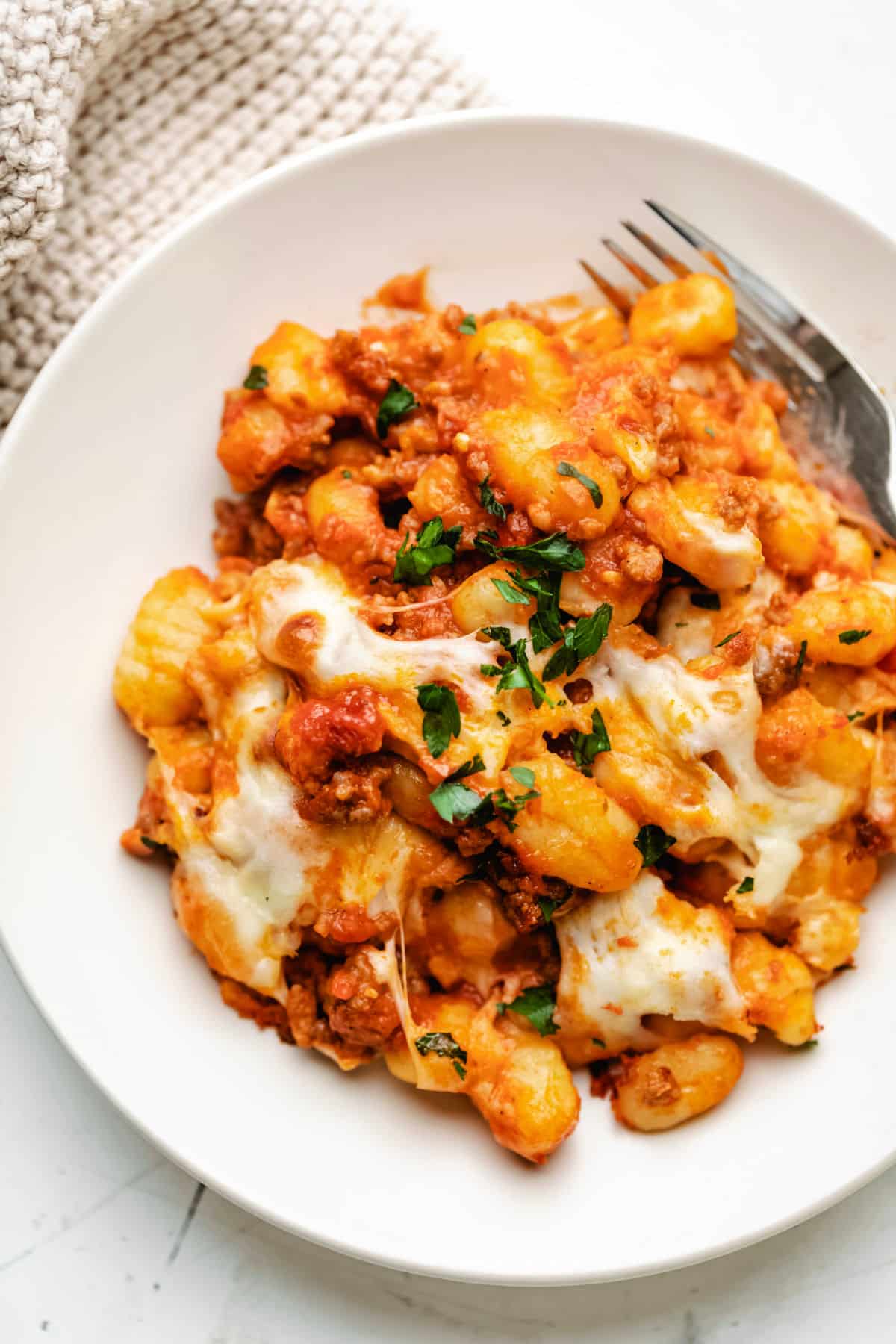 A plate of baked gnocchi topped with cheese and basil.