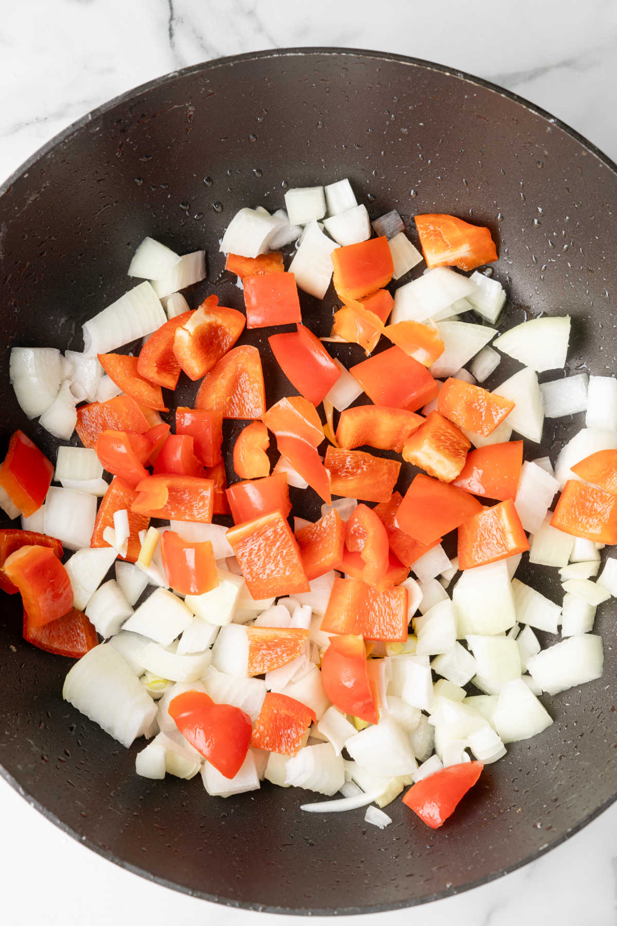 Pieces of chopped bell pepper and onion in a wok.