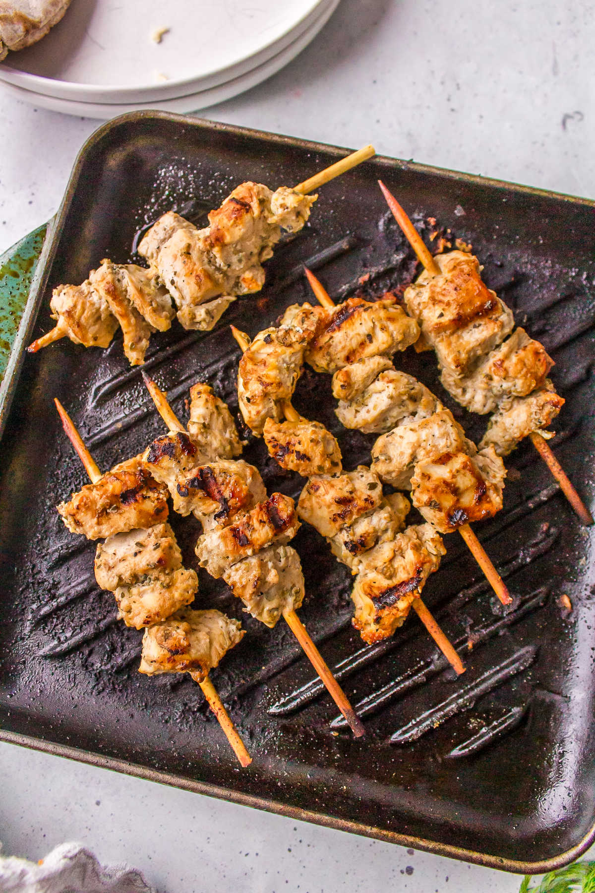 Grilled Greek chicken skewers on a grill pan.