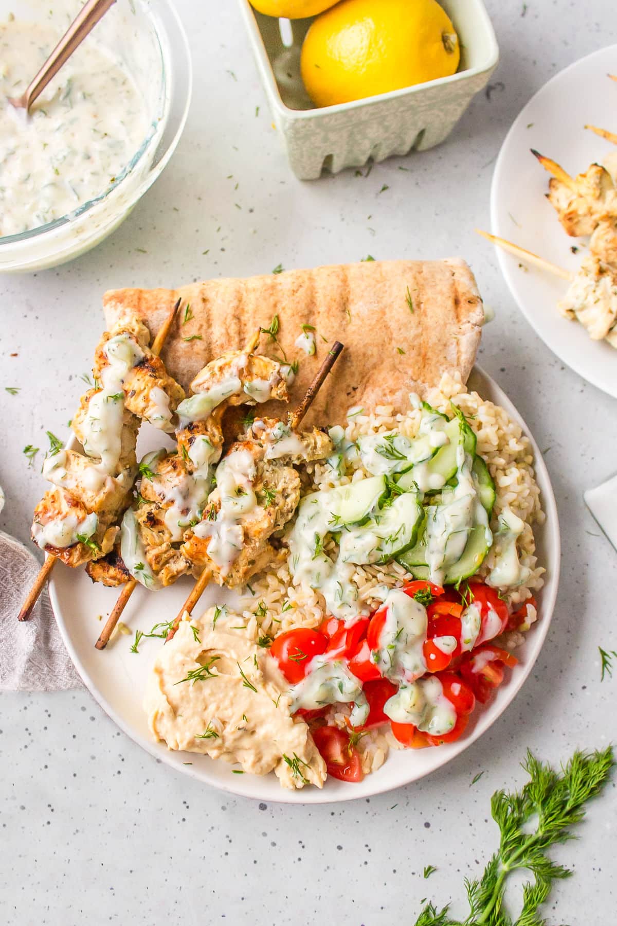 Greek chicken skewers on a bed of rice topped with tzatziki.