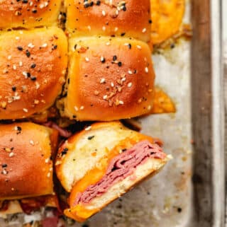 A baked roast beef slider on its side in a pan of baked sliders.