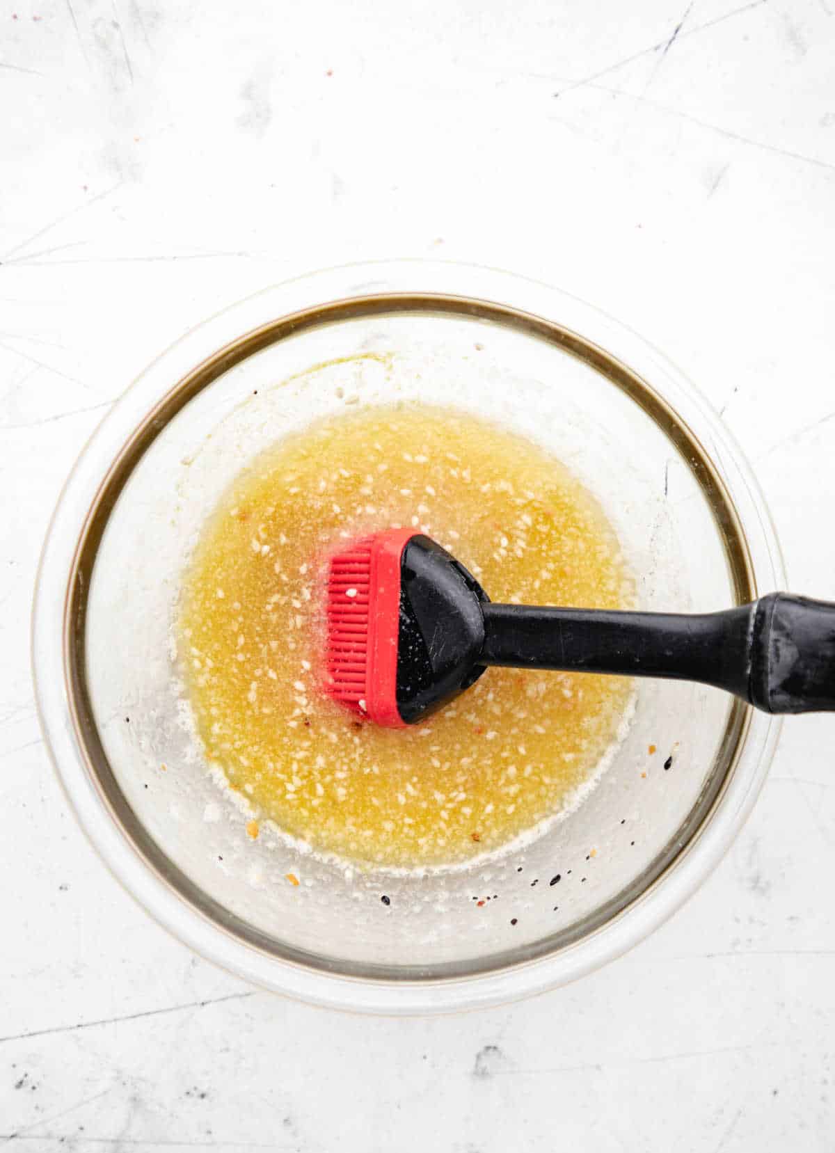 Butter topping in a glass mixing bowl with a basting brush in it.