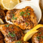 A spatula holding up a lemon herb chicken thigh from the pan.